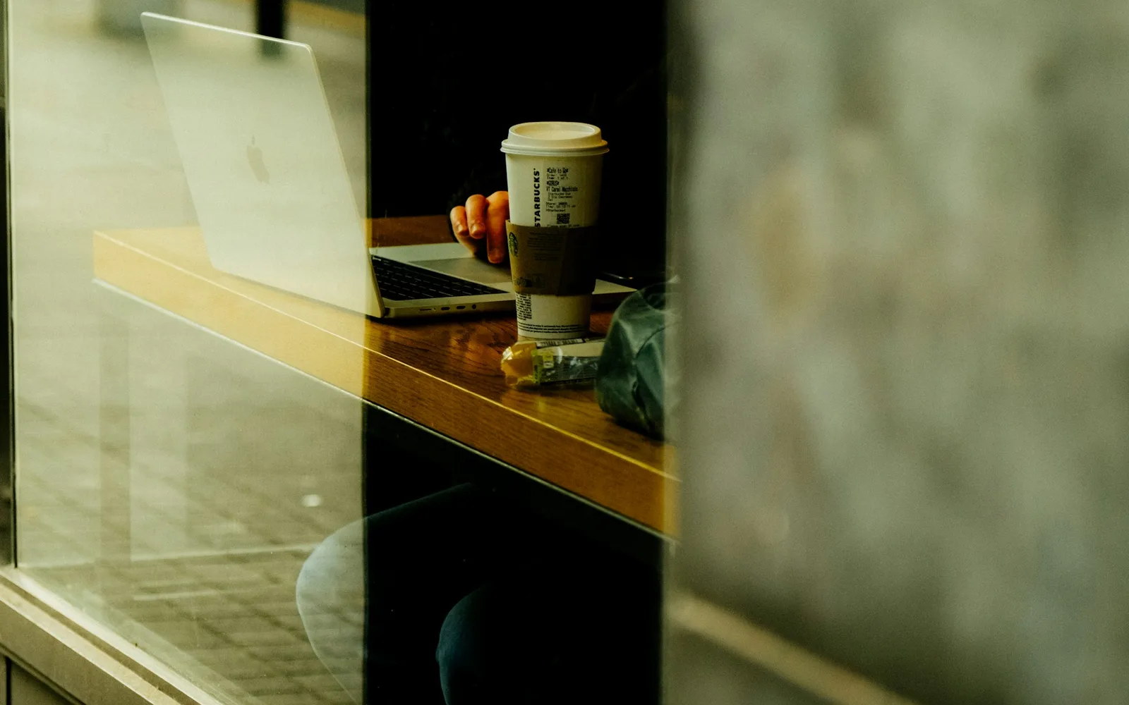Person working on a laptop with coffee inside a cafe