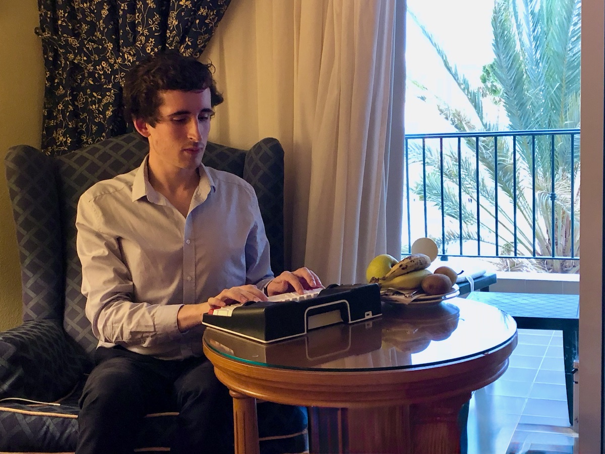 Pierre-Henry Soria playing a compact keyboard beside a window